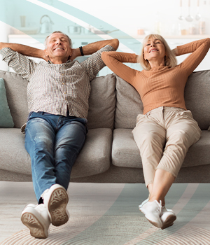 Couple sitting on couch with hands behind their heads showing relaxation