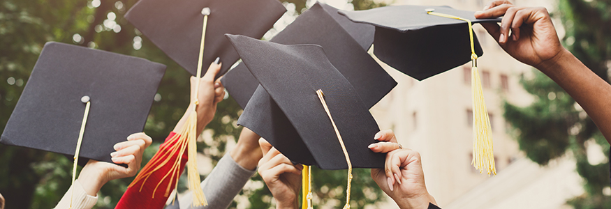 Hands holding up graduation caps celebrating thanks to scholarships